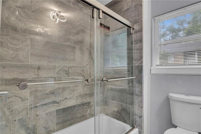 bathroom featuring plenty of natural light, a shower with shower door, and toilet