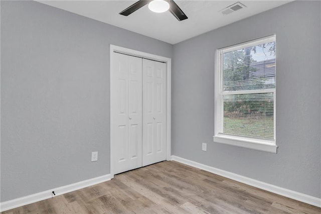 unfurnished bedroom with ceiling fan, multiple windows, and wood-type flooring