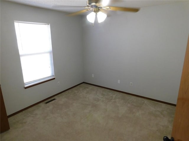 unfurnished room featuring visible vents, light carpet, baseboards, and a ceiling fan