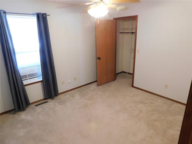 unfurnished bedroom with visible vents, light carpet, baseboards, and a ceiling fan