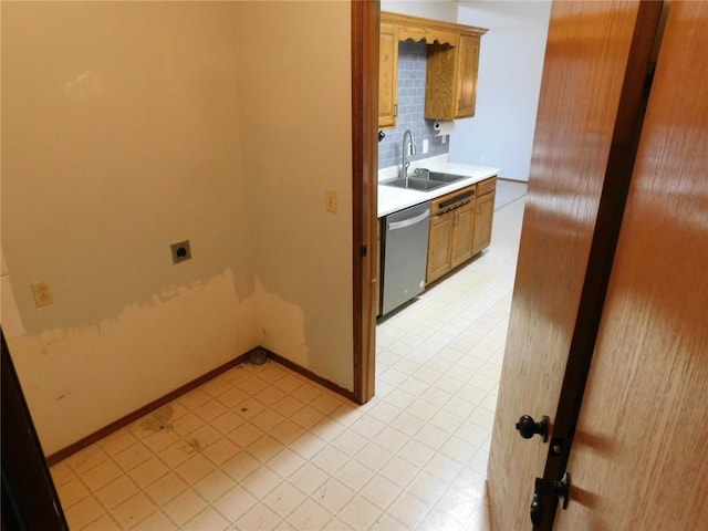 kitchen with light floors, a sink, light countertops, stainless steel dishwasher, and backsplash