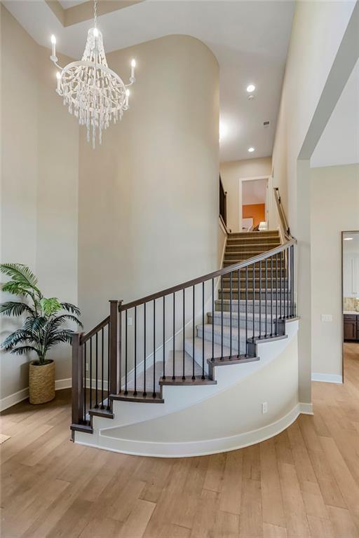 staircase with recessed lighting, a notable chandelier, baseboards, and wood finished floors