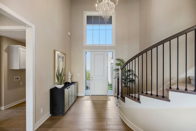 foyer entrance with a towering ceiling, dark wood-style flooring, stairway, and baseboards