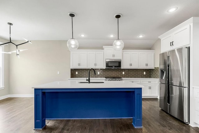 kitchen featuring appliances with stainless steel finishes, backsplash, dark hardwood / wood-style flooring, and an island with sink