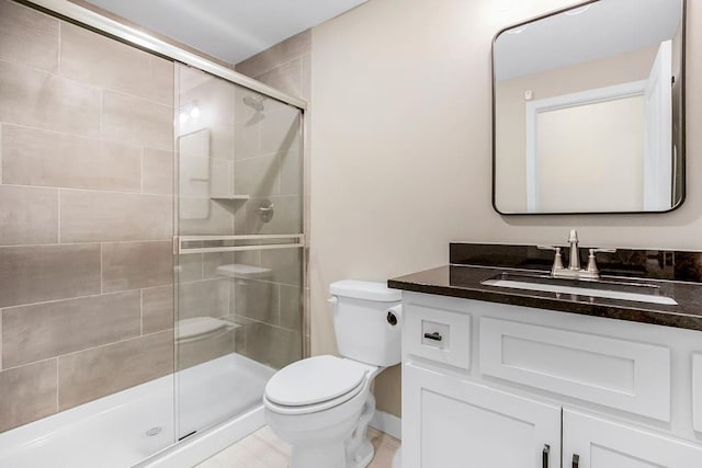 bathroom featuring toilet, a shower with door, and vanity