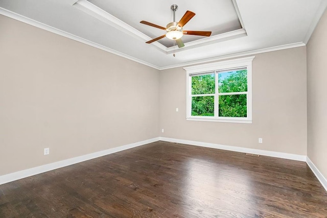 unfurnished room with ceiling fan, a tray ceiling, dark hardwood / wood-style floors, and ornamental molding