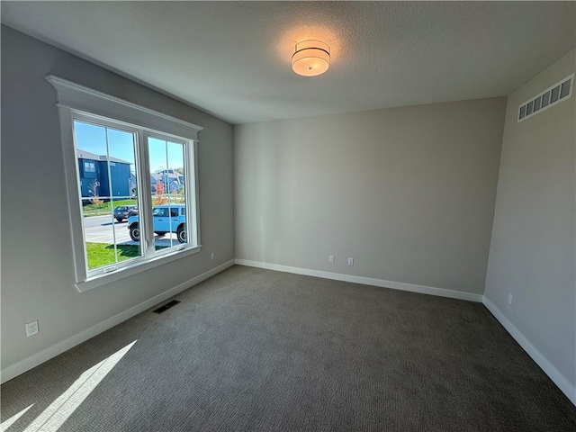 empty room featuring dark colored carpet and a textured ceiling