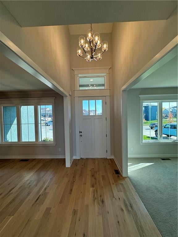 foyer with a chandelier, light wood-type flooring, and a high ceiling