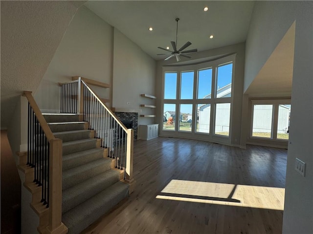 stairway featuring hardwood / wood-style flooring, high vaulted ceiling, and ceiling fan