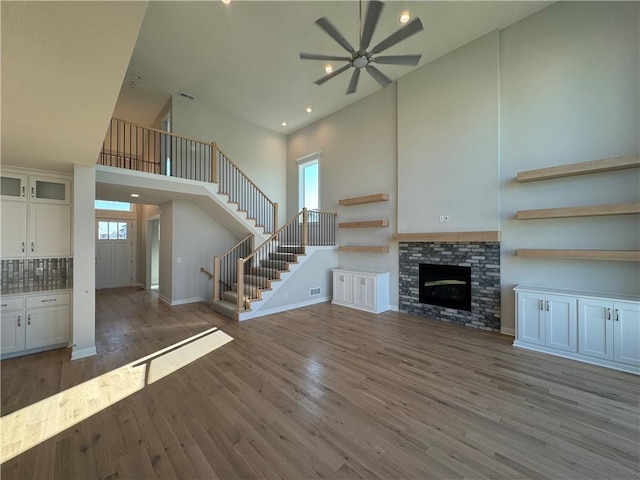 unfurnished living room featuring hardwood / wood-style floors, a fireplace, a towering ceiling, and plenty of natural light