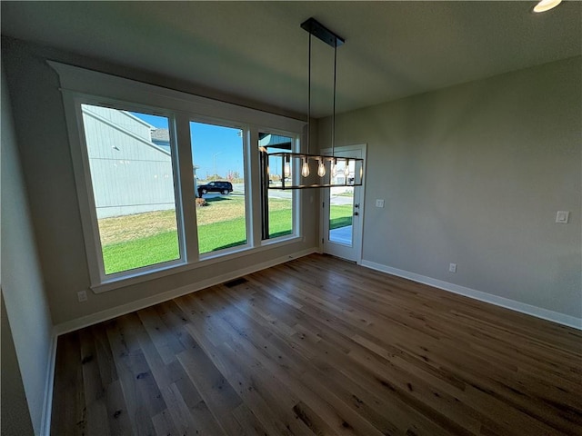 unfurnished dining area with a notable chandelier and dark hardwood / wood-style flooring