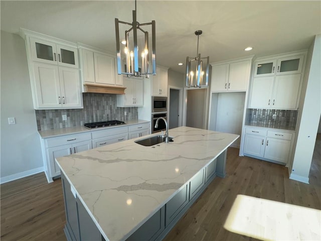 kitchen with sink, white cabinetry, and a kitchen island with sink