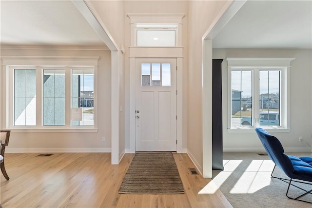 foyer with light wood finished floors, baseboards, and visible vents