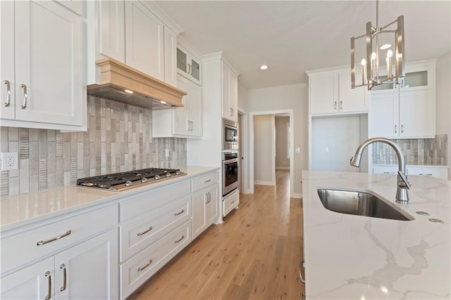 kitchen featuring stainless steel appliances, light wood-type flooring, a sink, and white cabinets