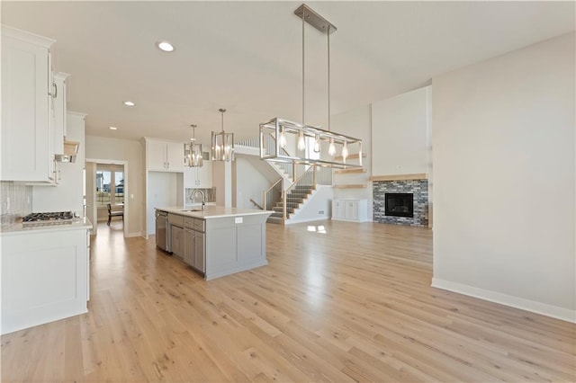 kitchen with white cabinets, open floor plan, appliances with stainless steel finishes, light wood finished floors, and tasteful backsplash