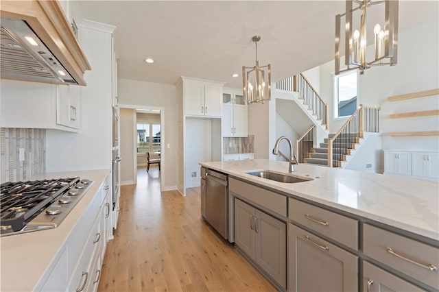 kitchen with an inviting chandelier, custom exhaust hood, stainless steel appliances, gray cabinetry, and a sink