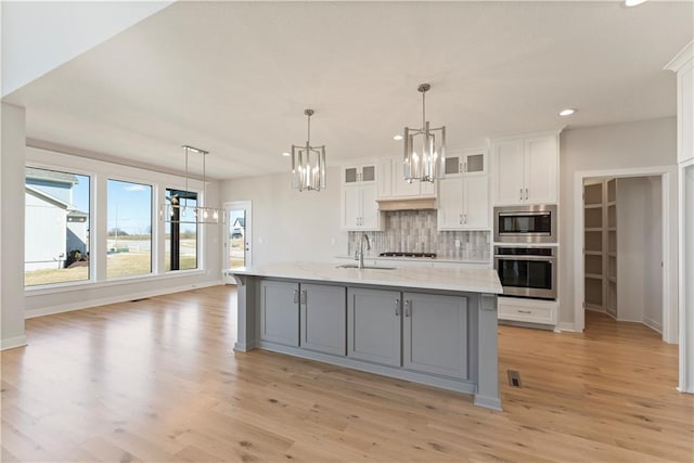 kitchen featuring white cabinets, appliances with stainless steel finishes, backsplash, gray cabinets, and a sink