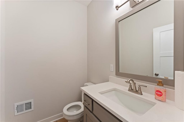 bathroom with toilet, vanity, visible vents, and baseboards