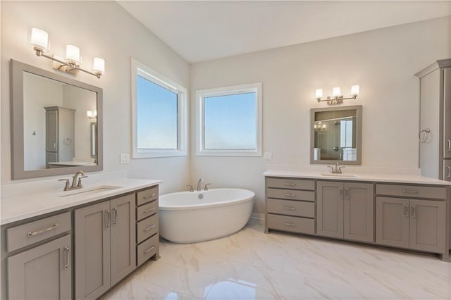 bathroom with marble finish floor, two vanities, a sink, and a freestanding bath