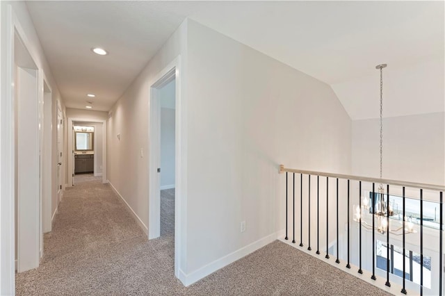 hall with baseboards, light colored carpet, an inviting chandelier, vaulted ceiling, and recessed lighting