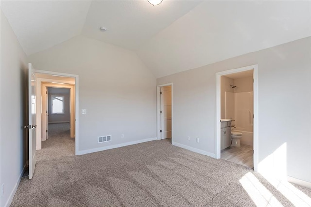 unfurnished bedroom with lofted ceiling, ensuite bathroom, visible vents, baseboards, and carpet