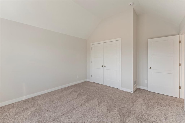 unfurnished bedroom featuring vaulted ceiling, a closet, carpet flooring, and baseboards