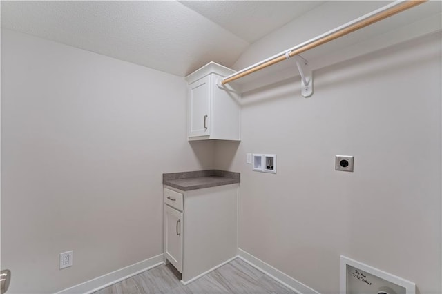 clothes washing area with hookup for an electric dryer, washer hookup, baseboards, cabinet space, and light wood finished floors