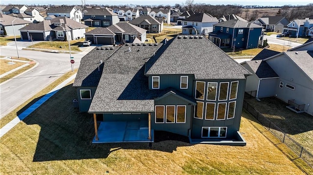 exterior space with roof with shingles, fence, and a residential view