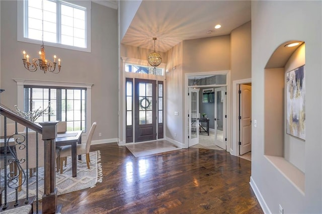 entrance foyer with hardwood / wood-style flooring, a towering ceiling, and an inviting chandelier