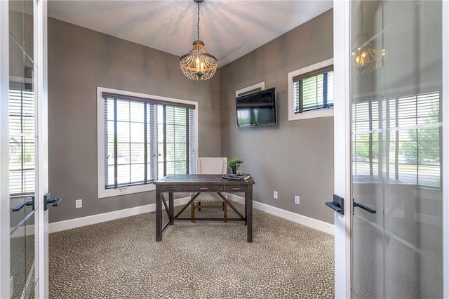 carpeted home office with french doors and an inviting chandelier