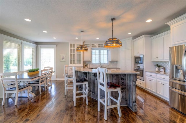 kitchen with light stone counters, a center island, white cabinets, and appliances with stainless steel finishes