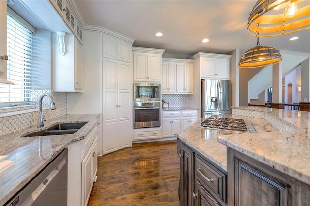 kitchen featuring white cabinetry, sink, hanging light fixtures, dark hardwood / wood-style floors, and appliances with stainless steel finishes