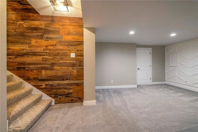 basement featuring carpet flooring and wooden walls