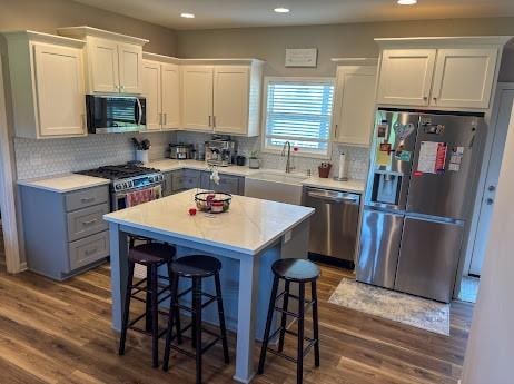 kitchen featuring appliances with stainless steel finishes, a center island, dark hardwood / wood-style flooring, and a breakfast bar area