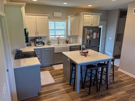 kitchen featuring a kitchen island, dark hardwood / wood-style flooring, tasteful backsplash, white cabinets, and black appliances