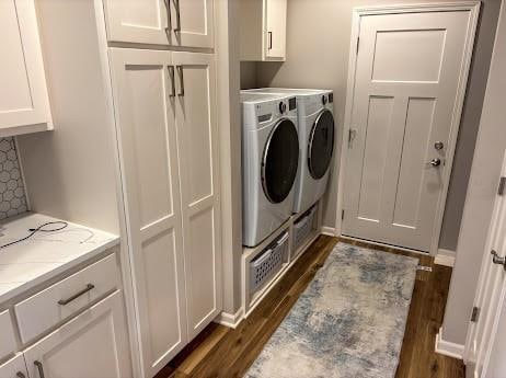 clothes washing area featuring washing machine and clothes dryer, dark hardwood / wood-style floors, and cabinets