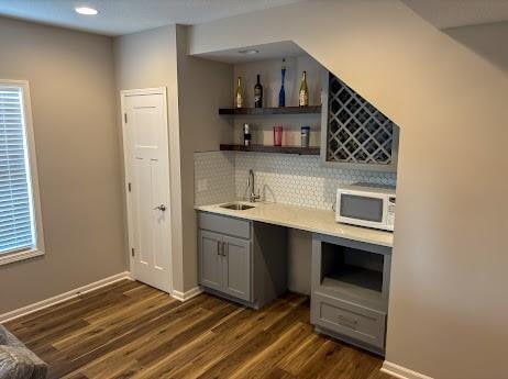 bar featuring dark hardwood / wood-style floors, sink, gray cabinets, and decorative backsplash