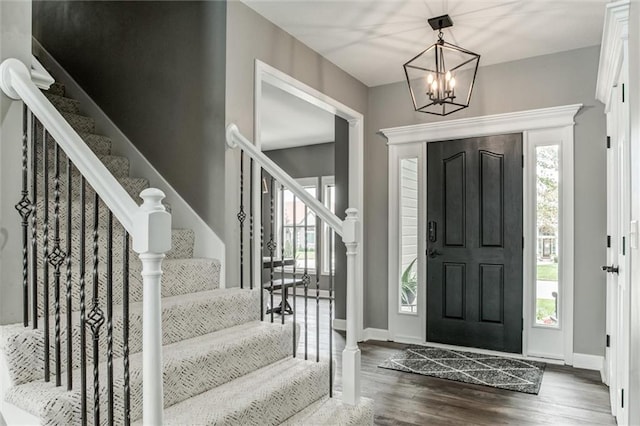 foyer with plenty of natural light, an inviting chandelier, and hardwood / wood-style floors