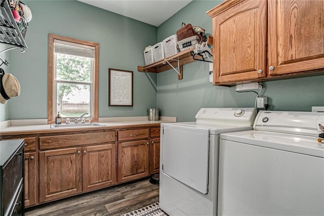 laundry area featuring sink, washing machine and dryer, dark hardwood / wood-style flooring, and cabinets