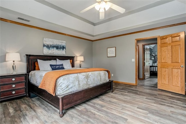 bedroom featuring hardwood / wood-style floors, a raised ceiling, and ceiling fan