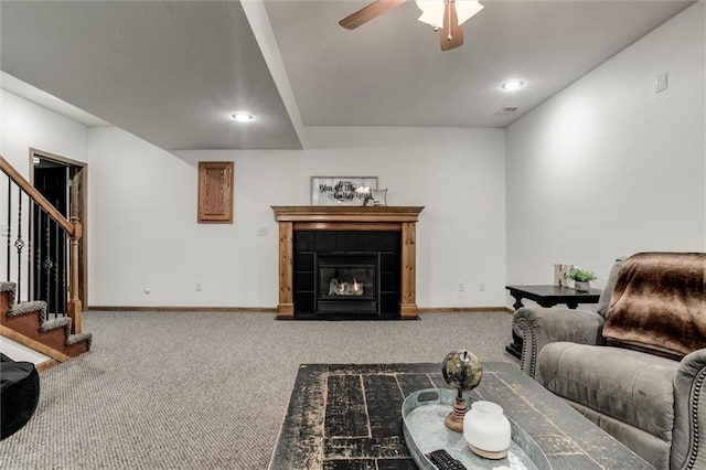 carpeted living room with ceiling fan and a tiled fireplace