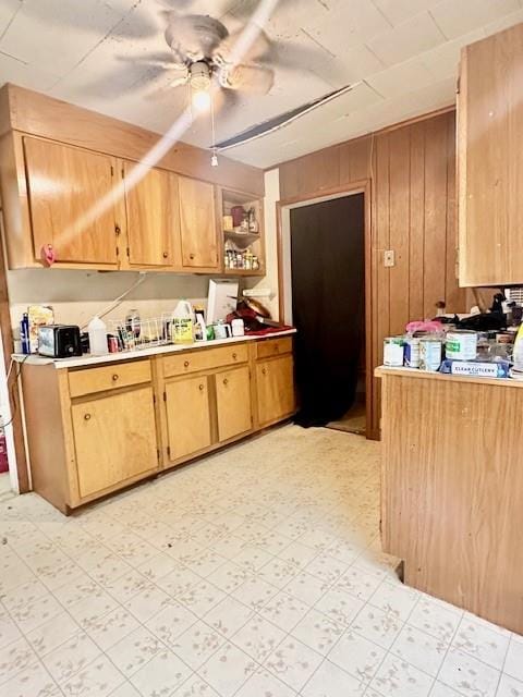 kitchen with wooden walls, ceiling fan, and light tile patterned floors