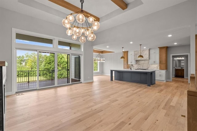 8732 N Lewis Ave, Kansas City, MO 64157 - unfurnished living room with a sink, a chandelier, light wood-type flooring, baseboards, and beamed ceiling