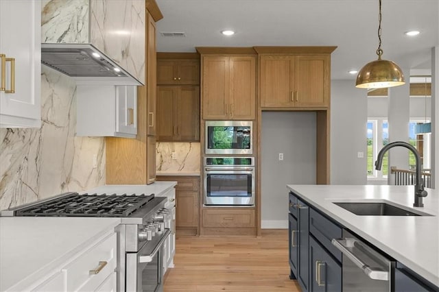 8732 N Lewis Ave, Kansas City, MO 64157 - kitchen with stainless steel appliances, a sink, custom exhaust hood, light countertops, and light wood finished floors