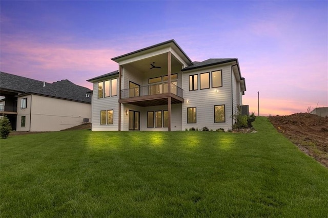 8732 N Lewis Ave, Kansas City, MO 64157 - back of property at dusk featuring a balcony, a yard, and ceiling fan