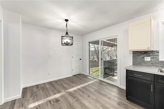 unfurnished dining area featuring an inviting chandelier and light hardwood / wood-style floors