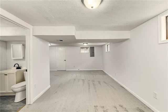 basement featuring sink, light colored carpet, electric panel, and a textured ceiling