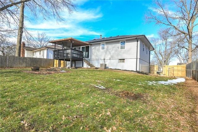 rear view of property with cooling unit, a wooden deck, and a lawn