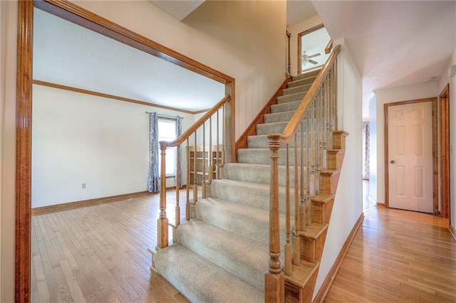 stairway with ornamental molding and hardwood / wood-style floors