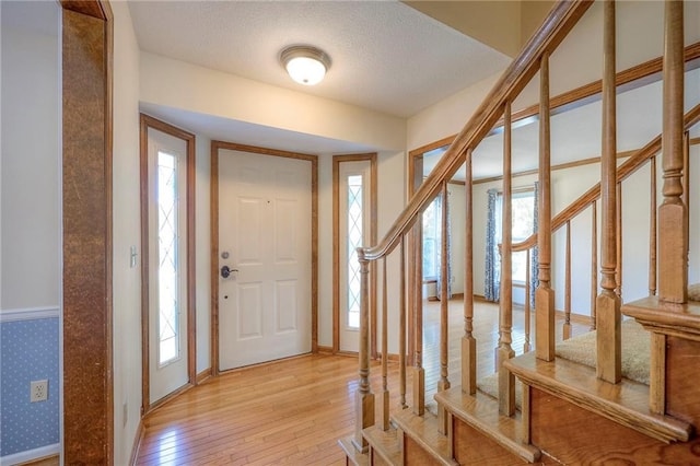 entryway with plenty of natural light, light hardwood / wood-style flooring, and a textured ceiling